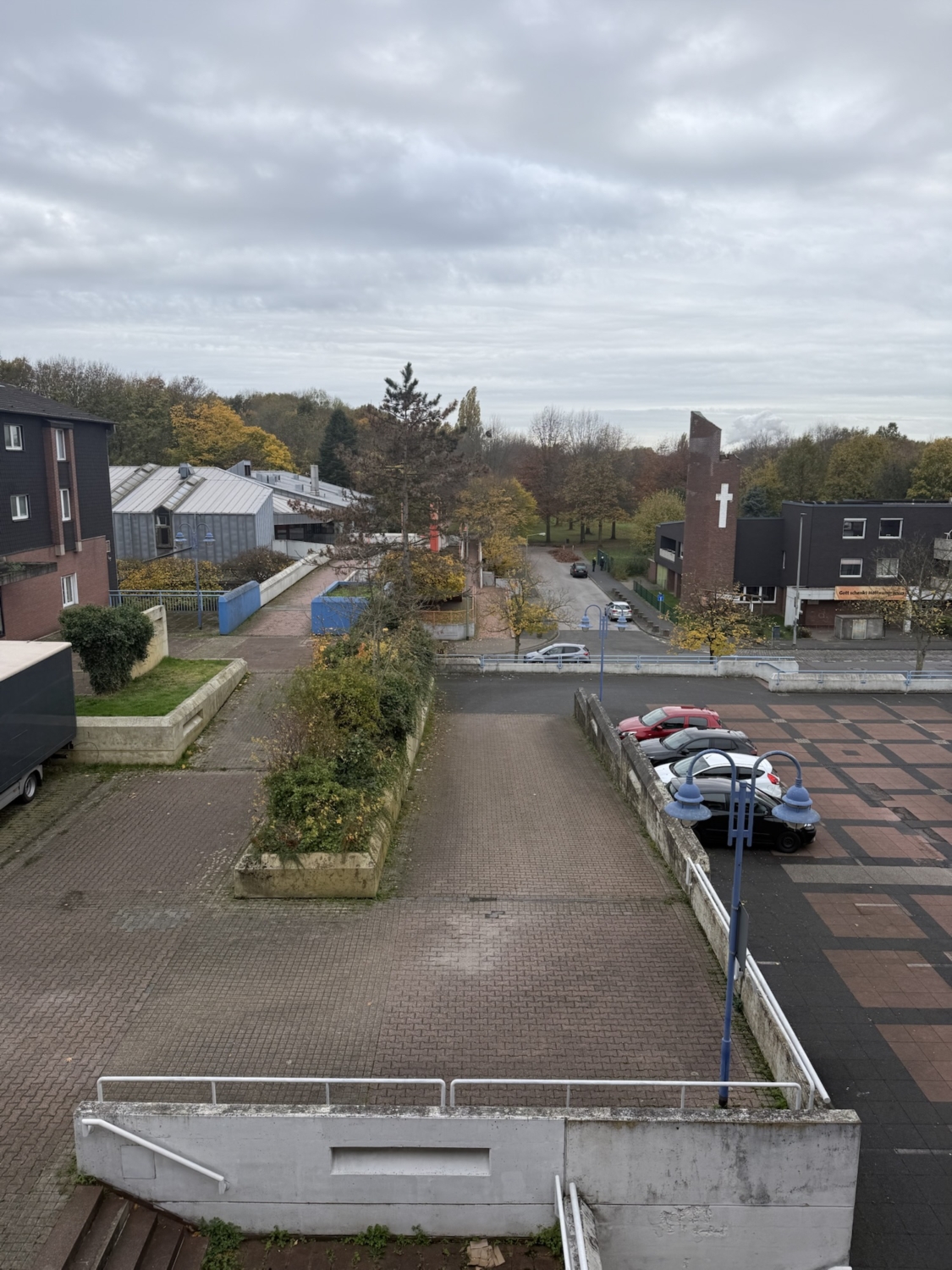 Blick auf einen Parkplatz mit mehreren Autos und einer angrenzenden Straße in einer städtischen Umgebung.