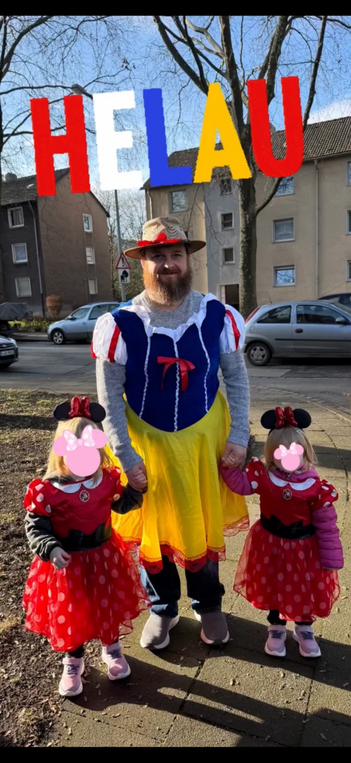 Ein Mann in einem Schneewittchen-Kost&uuml;m steht mit zwei M&auml;dchen in roten Kleidern mit Punkten auf einer Stra&szlig;e.