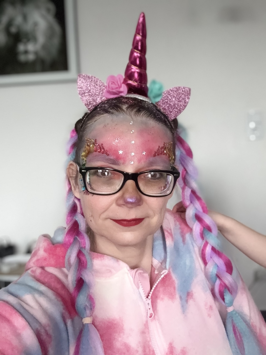 Frau mit Einhorn-Haarreif, bunten Z&ouml;pfen und Gesichtsbemalung in einem pastellfarbenen Outfit.