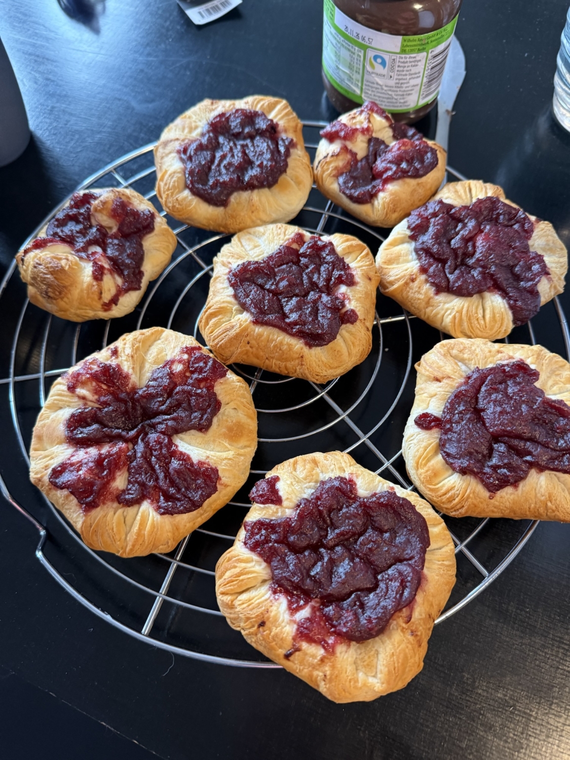 Frisch gebackene Plundergeb&auml;cke mit roter Marmelade auf einem Kuchengitter.