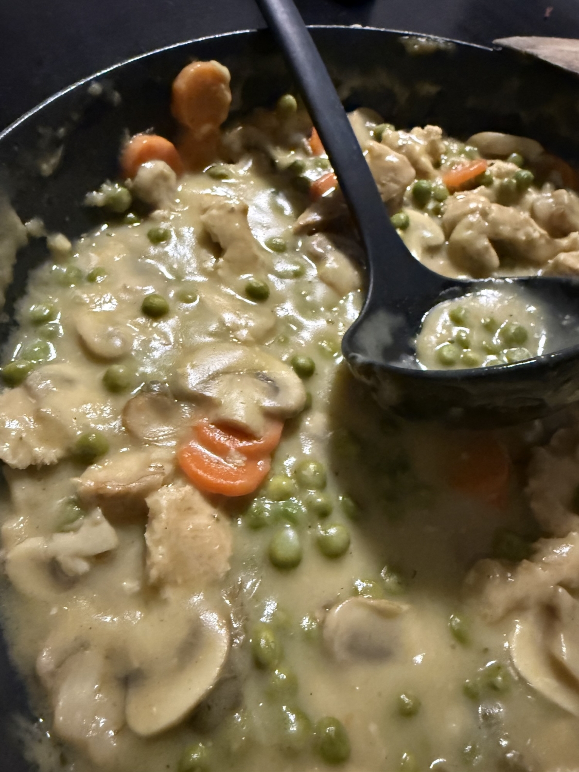 Ein Gericht mit veganen H&auml;hnchen, Erbsen, Karotten und Pilzen in einer cremigen Sauce in einer Sch&uuml;ssel.